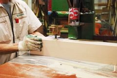 Factory worker cutting the wood with the machine